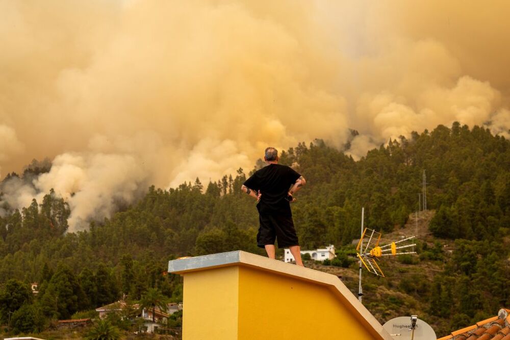 Un vecino observa desde el tejado de una casa el incendio forestal declarado en  la Palma, cerca de una vivienda, a 15 de julio de 2023, en Puntagorda, La Palma, Canarias (España). Este incendio declarado en la madrugada de hoy en zona urbano forestal en 