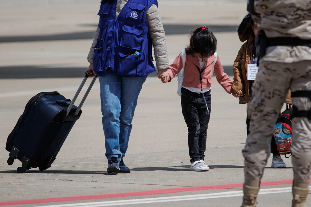 Una niña procedente de Siria de la mano de una trabajadora de una organización a su llegada a la base aérea de Torrejón de Ardoz